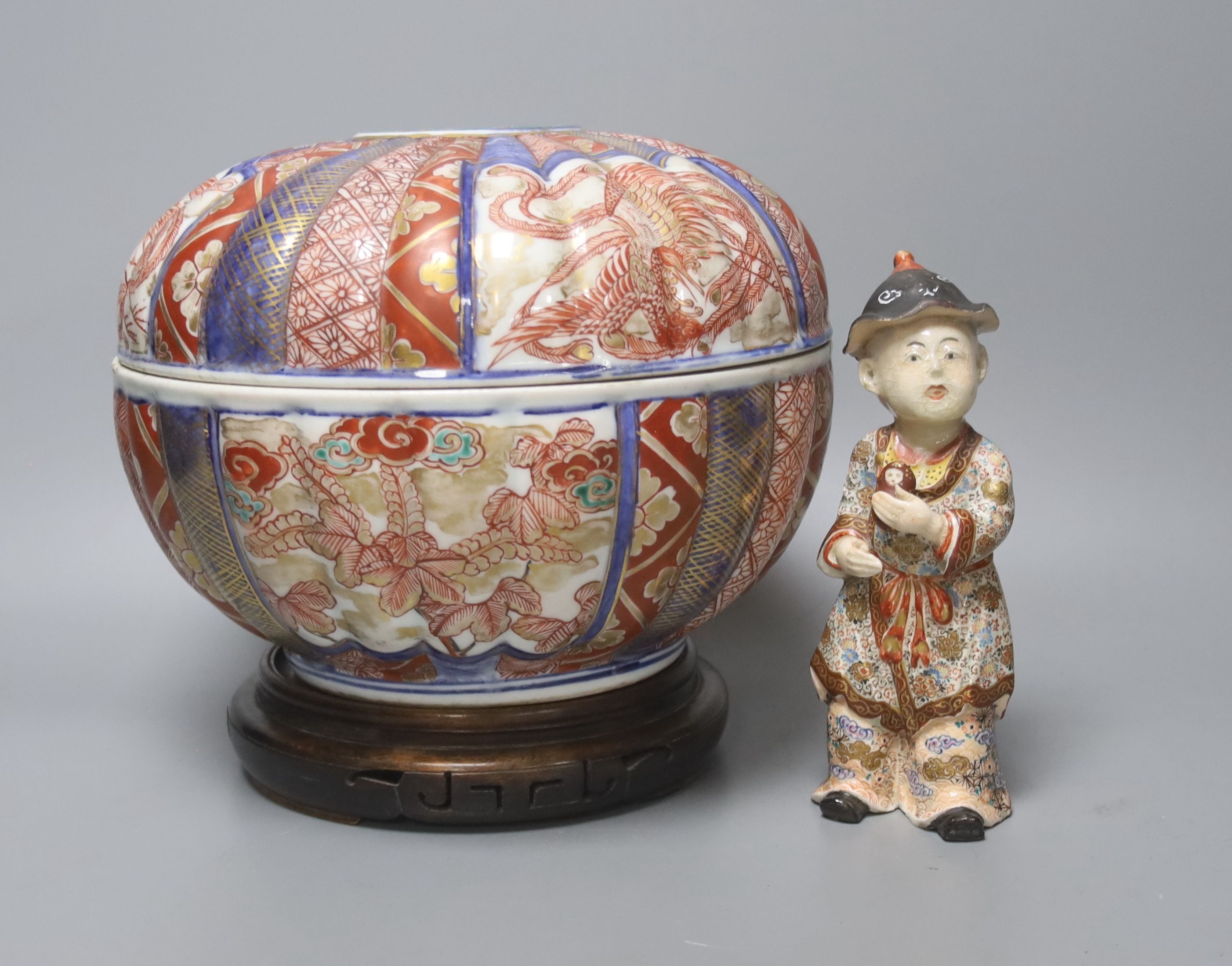 A 19th century Japanese Imari box and cover and a Satsuma pottery figure of a boy holding a Daruma doll, tallest 20cm